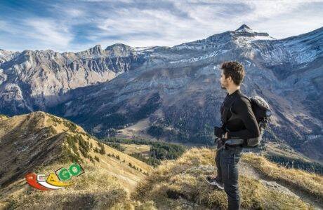 Парень с рюкзаком на плечах стоит в горах